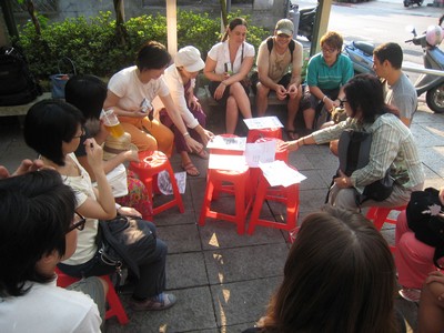 Students sitting in a circle around red chairs with paper on them