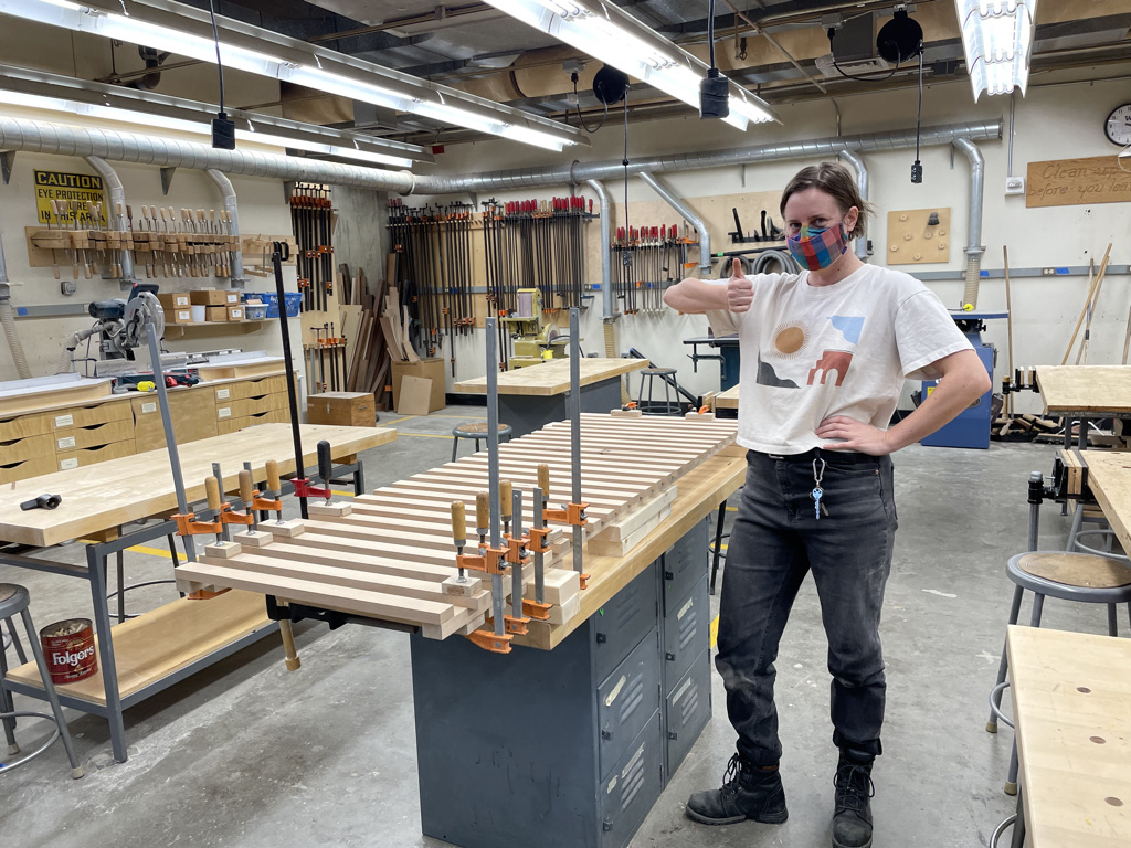Person giving a thumbs up standing next to their project in the fabrication lab