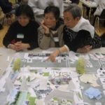 Women looking at model of open space during workshop