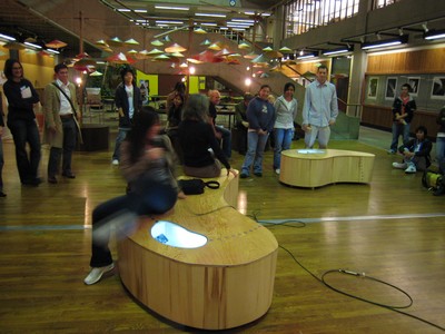 Students sitting on wooden bench under pendant lights