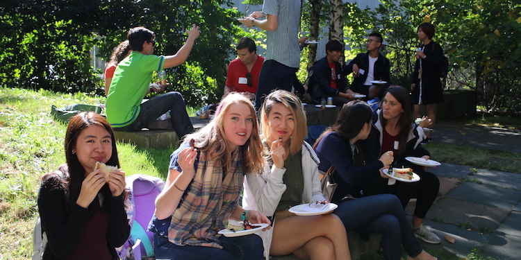 students sitting outside and smiling for the camera as they eat lunch