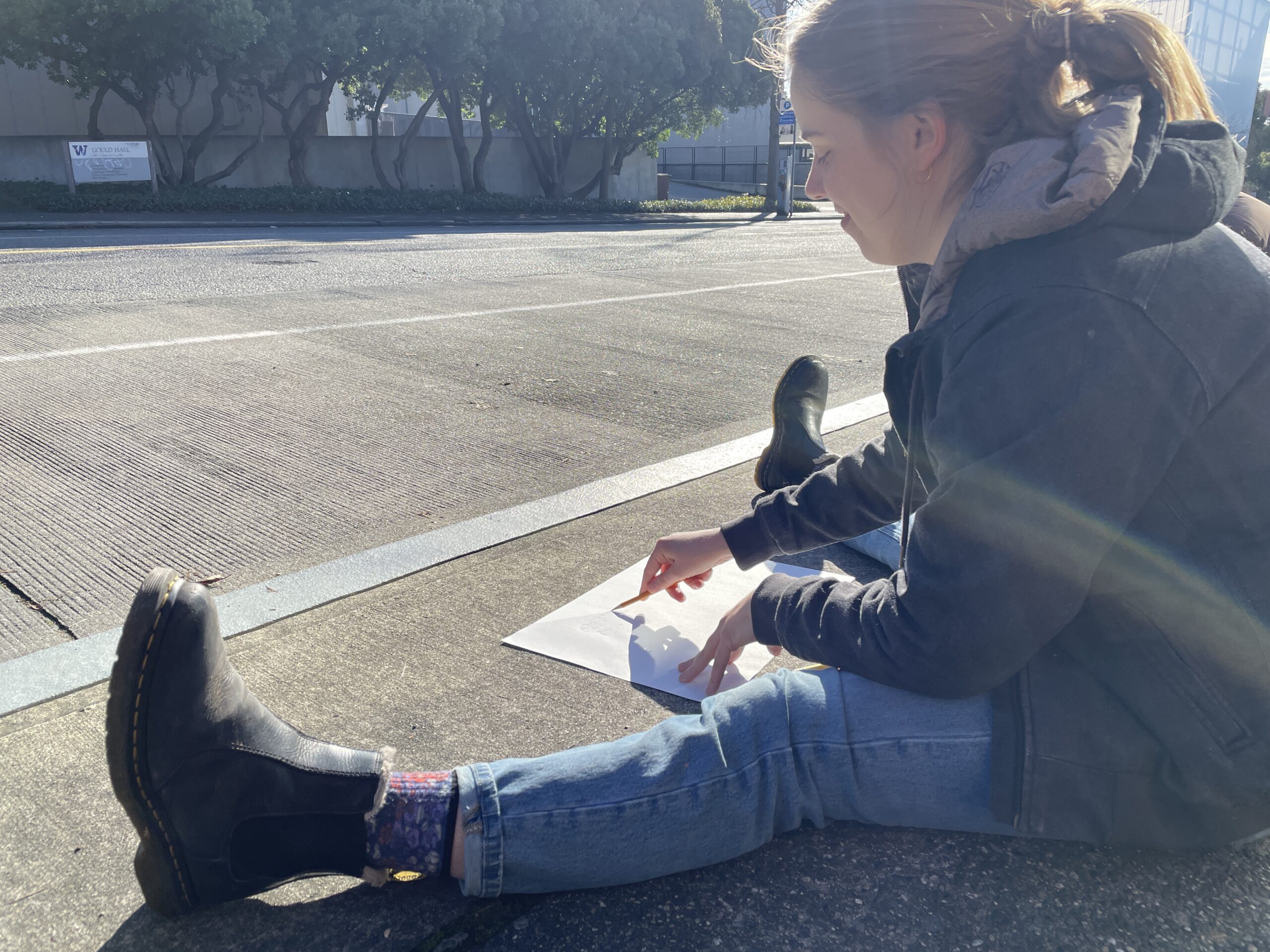 person sitting on the ground drawing on a piece of paper