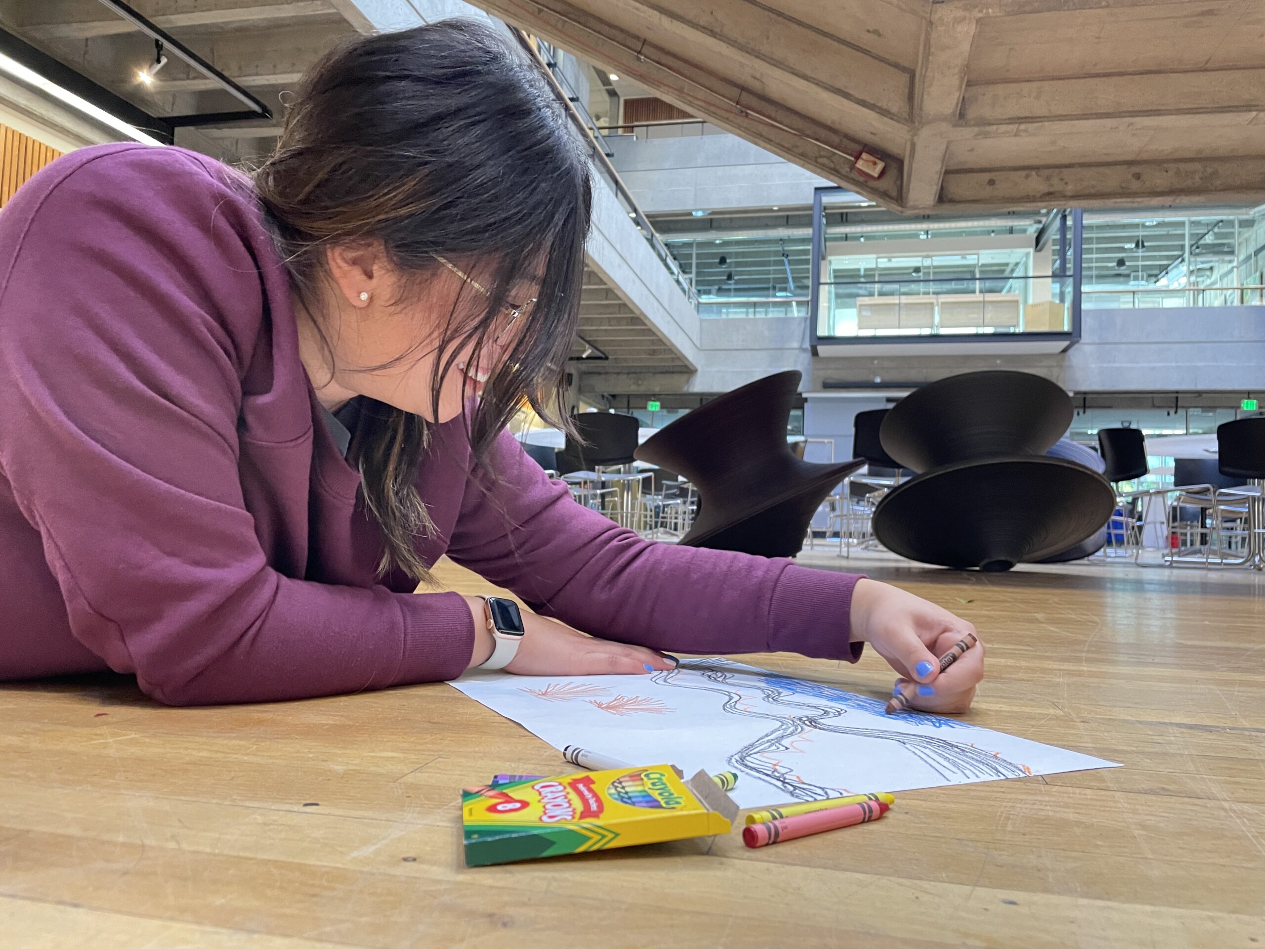 Person laying on ground drawing with crayons