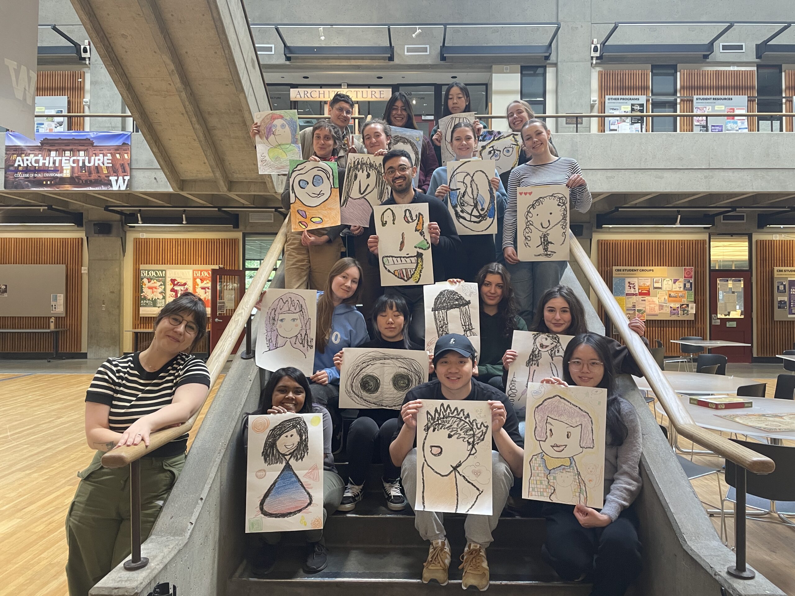 Group of participants sitting on a staircase each holding their drawings