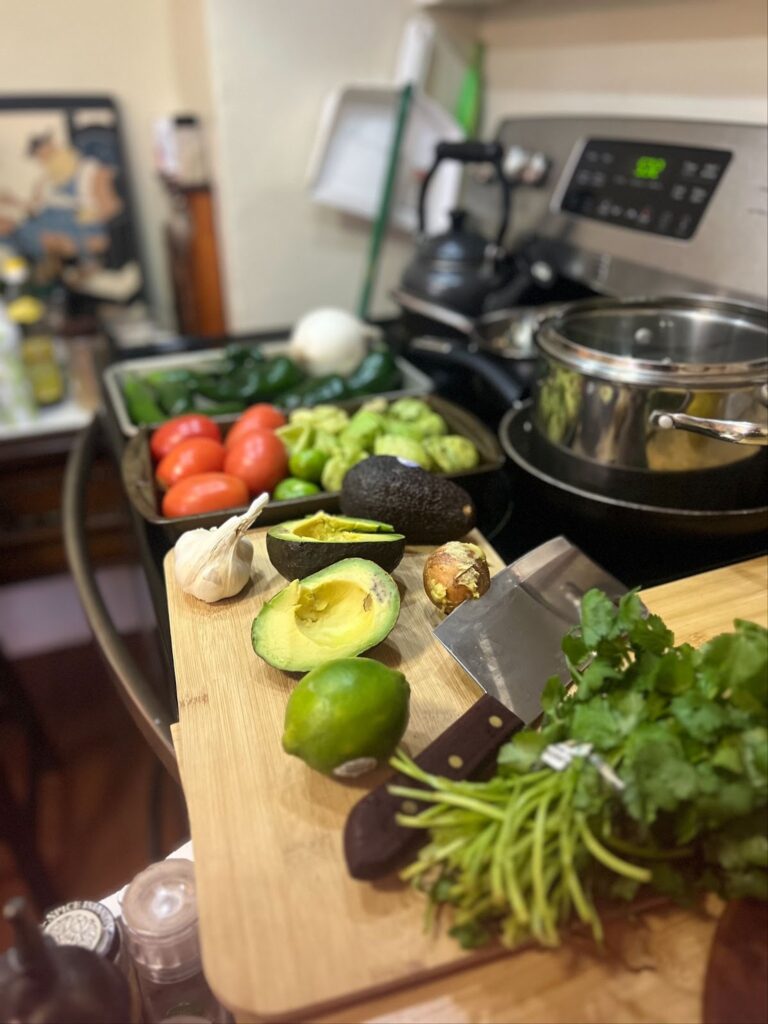 tomato and peppers and avocado and lime and knife and cutting board and cilantro on stove in kitchen